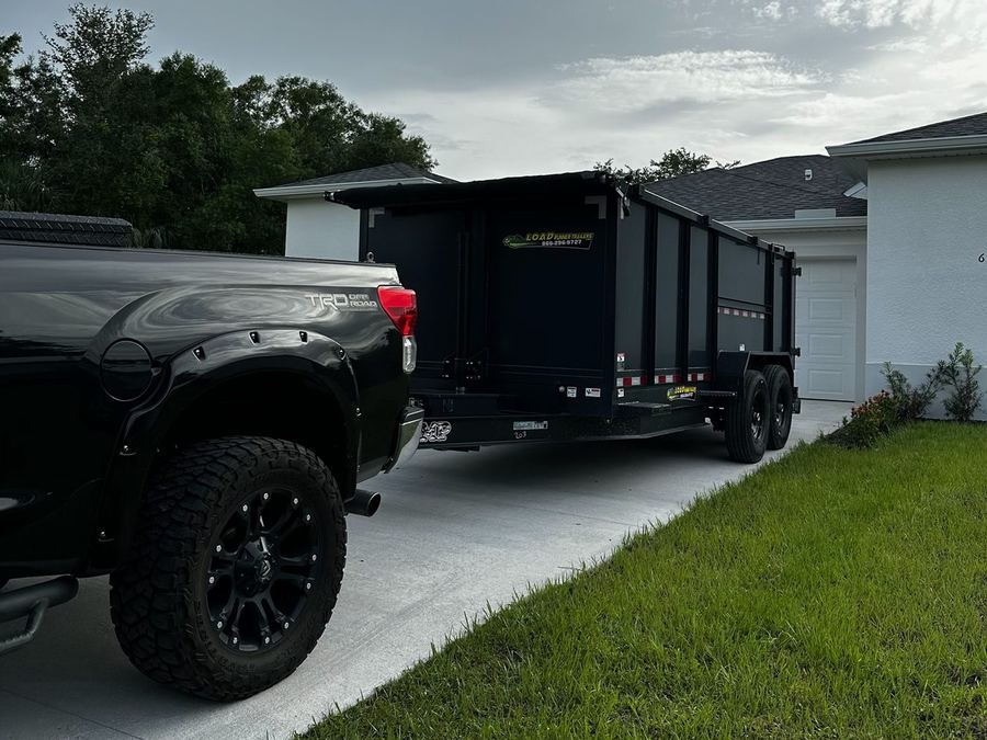 Apex Removal Solutions black pickup truck and dump trailer parked in a home driveway